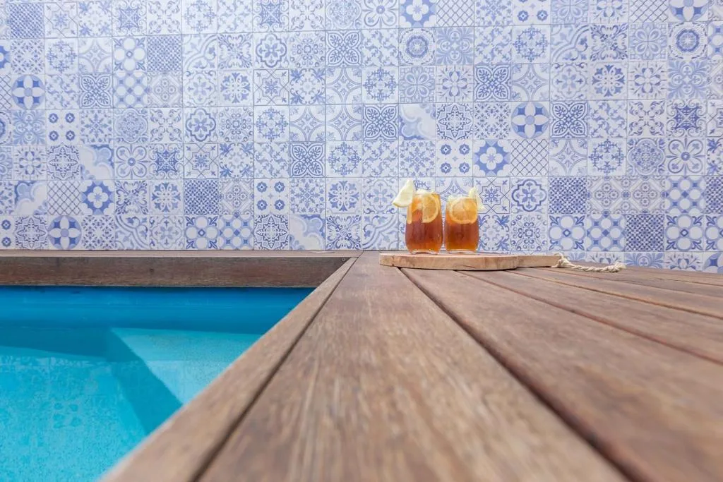 Swimming pool with blue water, wooden deck, and decorative tile backdrop