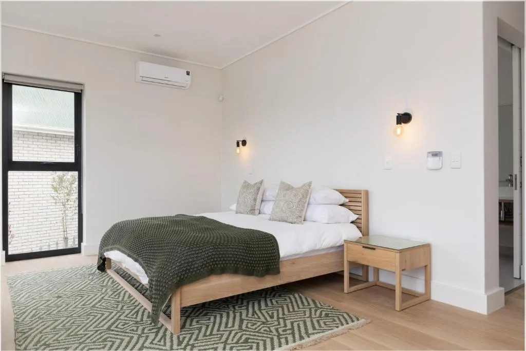 Bright bedroom with wooden bed, green bedding, and contemporary wall sconces