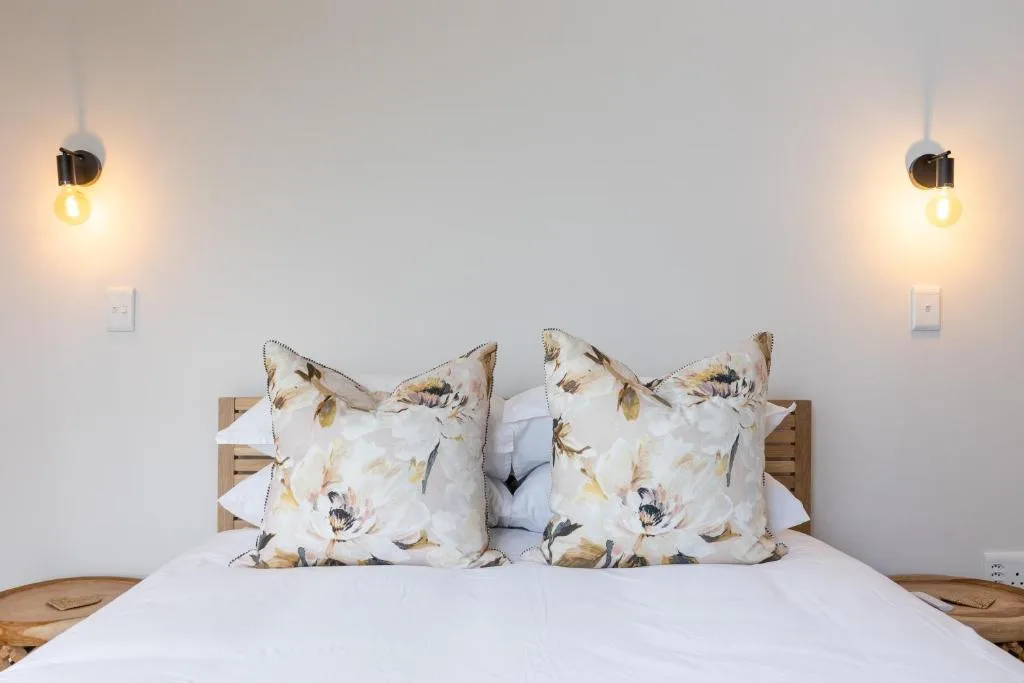 Modern bedroom with floral pillows, wooden headboard, pendant lights