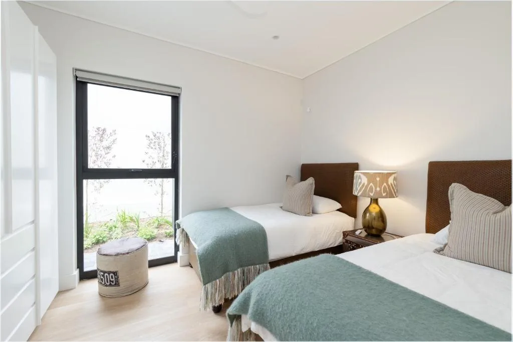 Bright bedroom with two beds, brown headboards, and garden view doors