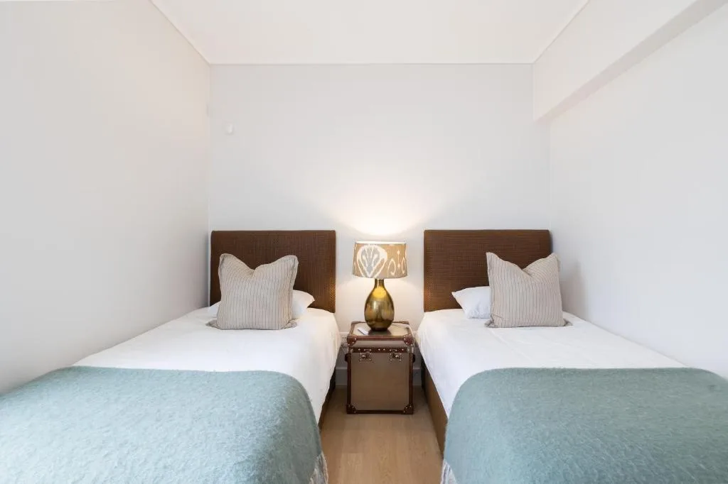 Twin bedroom with white walls, wooden headboards, and blue throws