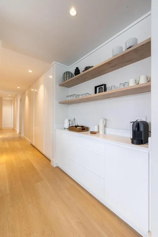 Modern hallway with wooden shelving, white cabinetry, and warm lighting