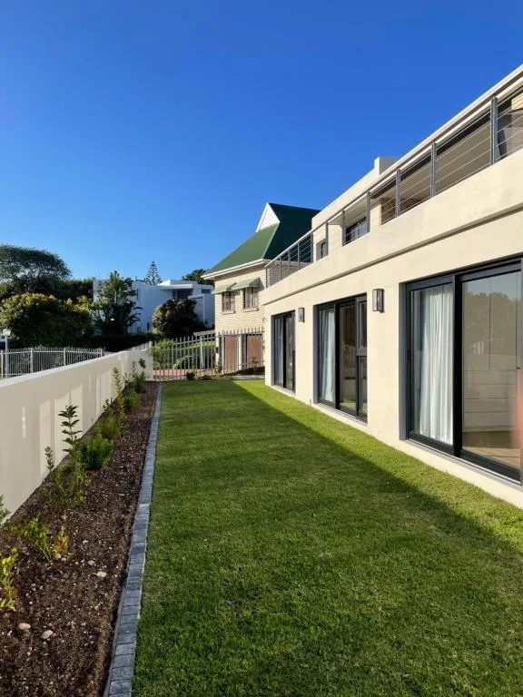 Modern villa exterior with manicured lawn and white fence boundary