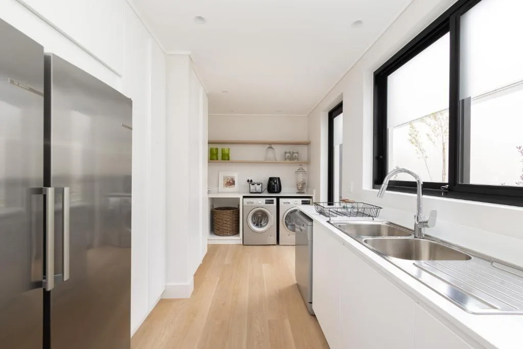 Modern kitchen with stainless steel sink, appliances, and bright windows