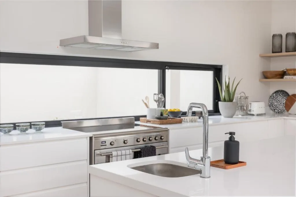 Modern kitchen with stainless steel appliances, white counters, and open shelving