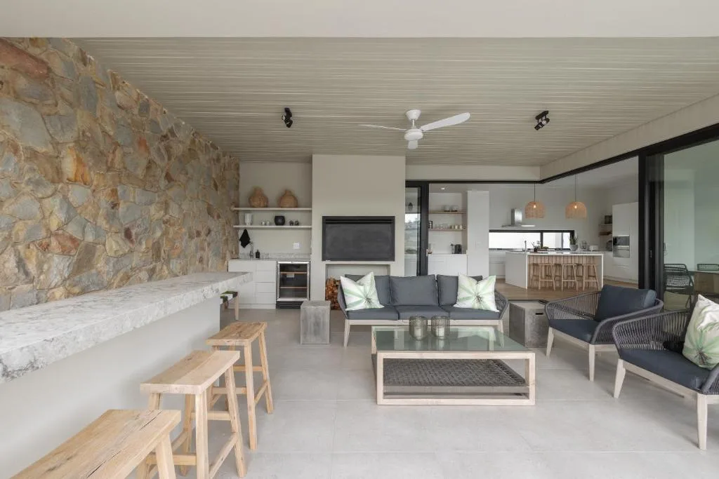 Open-plan lounge with gray sofas, stone fireplace, and kitchen visible beyond
