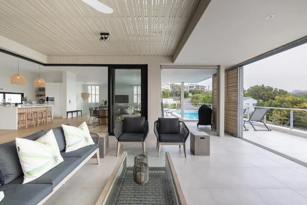 Modern lounge with black chairs, sofa, and deck views of pool