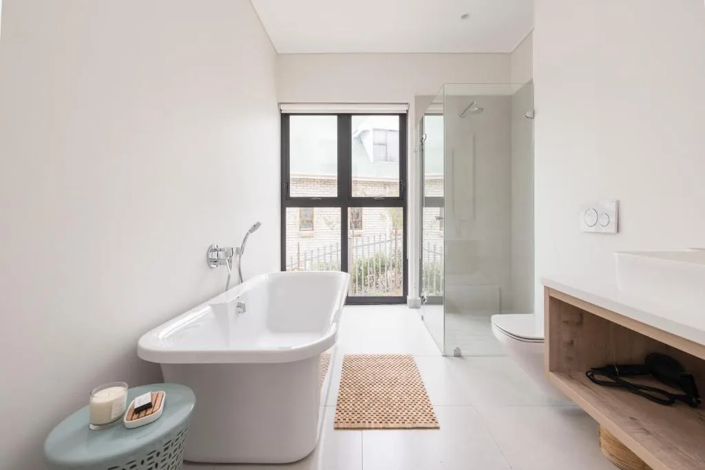 Modern bathroom with freestanding white bathtub and glass shower enclosure