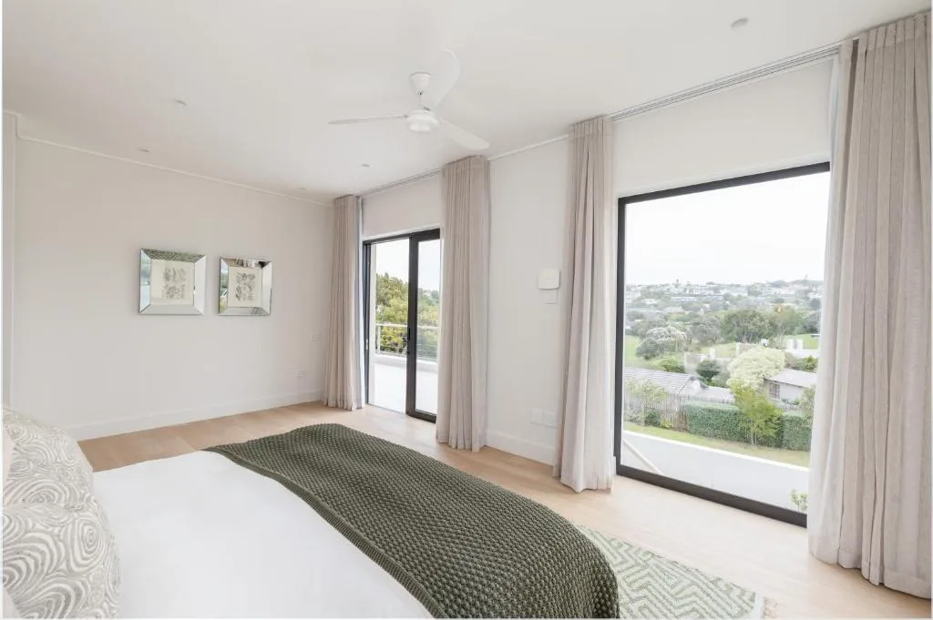 Spacious bedroom with queen bed, garden views through large sliding doors