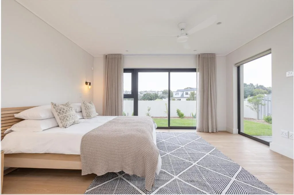 Bright bedroom with queen bed and sliding doors opening to garden view