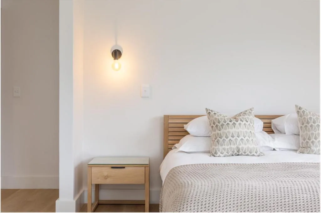 Bright bedroom with wooden bed frame and patterned cushions, pendant light
