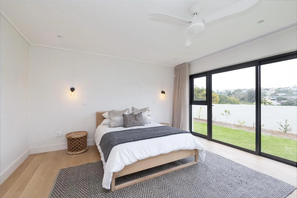 Spacious bedroom with queen bed, garden views through large windows