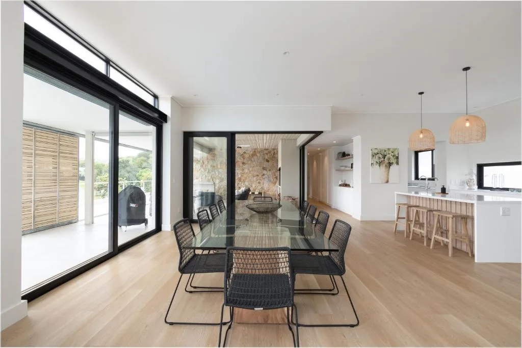 Modern dining area with black glass table and contemporary chairs overlooking kitchen