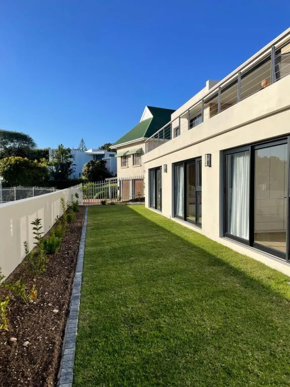 Modern cream villa with manicured lawn, landscaping, and large sliding doors