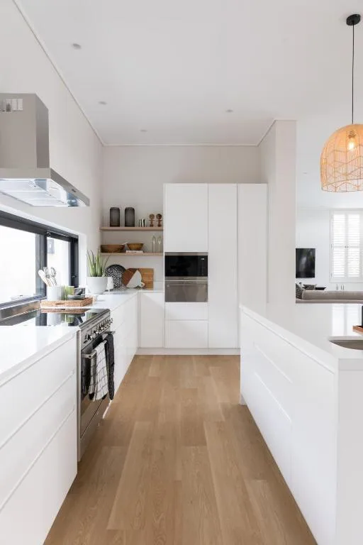 Modern white kitchen with stainless steel appliances and wooden flooring