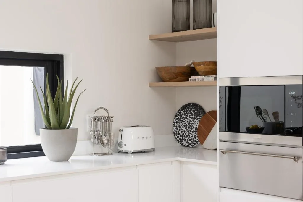 Modern white kitchen with stainless steel appliances and open shelving
