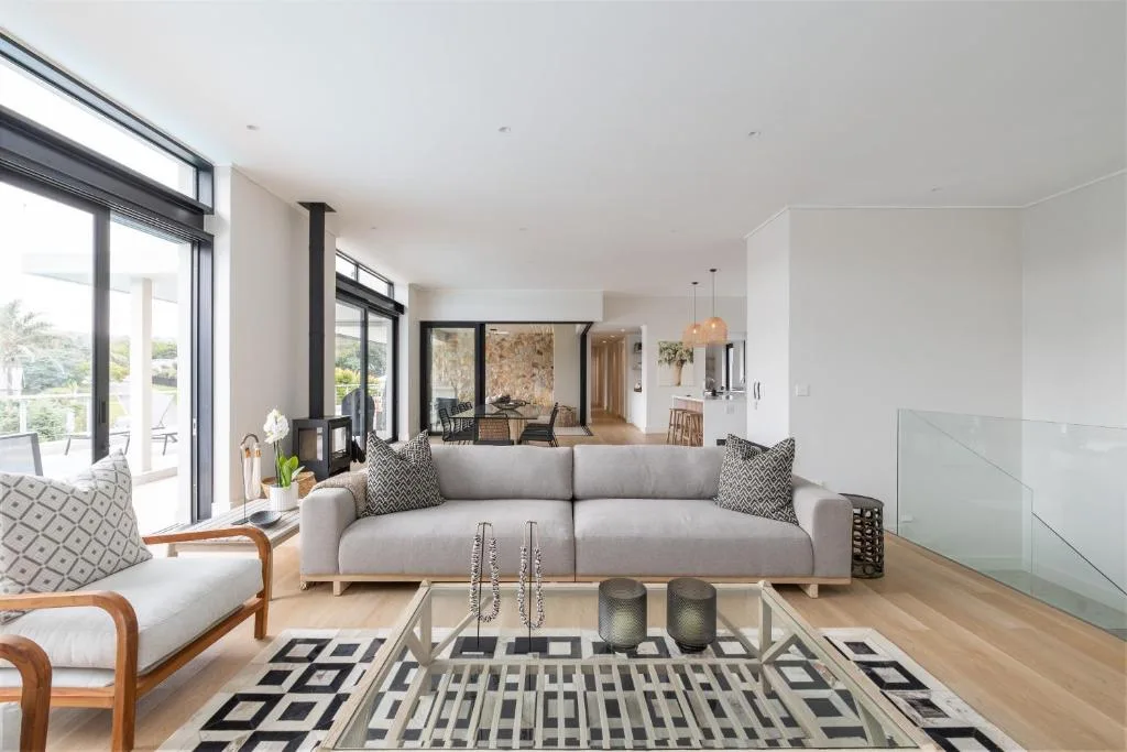 Modern lounge with gray sofa, wooden armchair, and geometric rug
