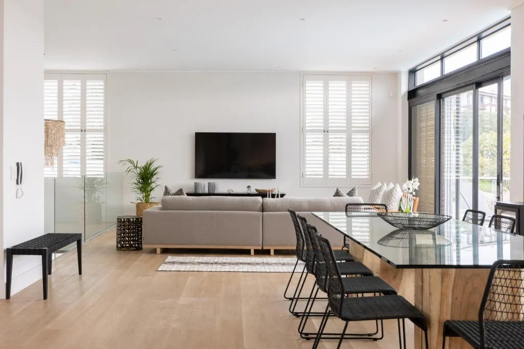 Modern lounge with gray sofa, TV, and dining area visible beyond