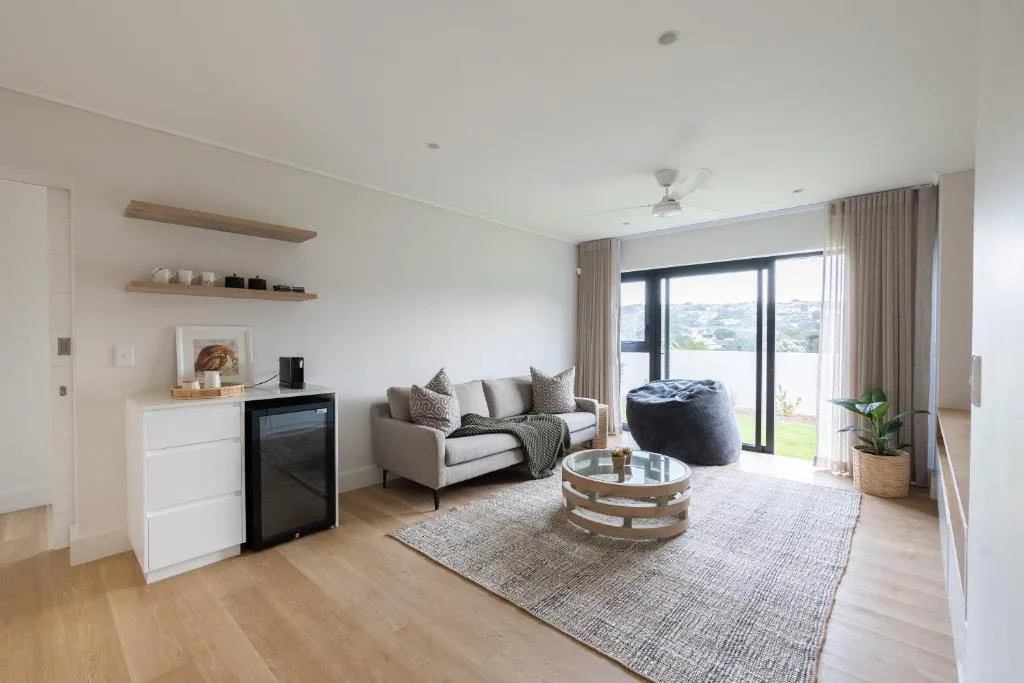 Modern lounge with cream sofa, coffee table, and scenic valley views through large glass doors