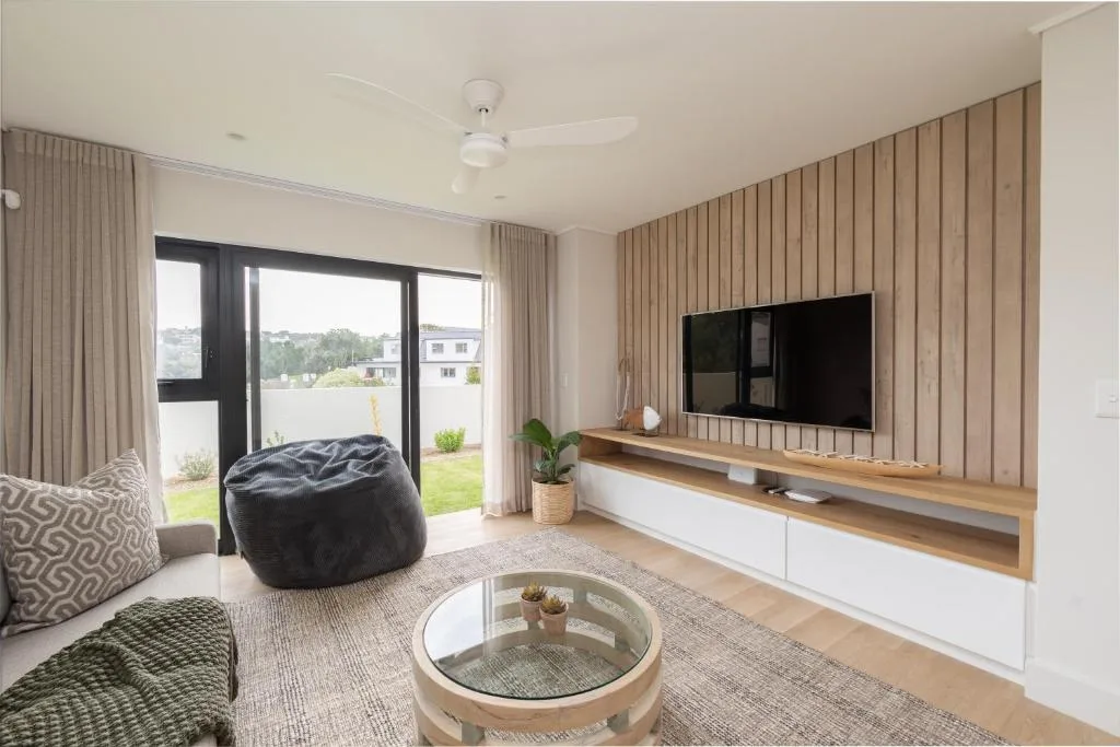 Modern living room with TV, bean bag chair, and deck access