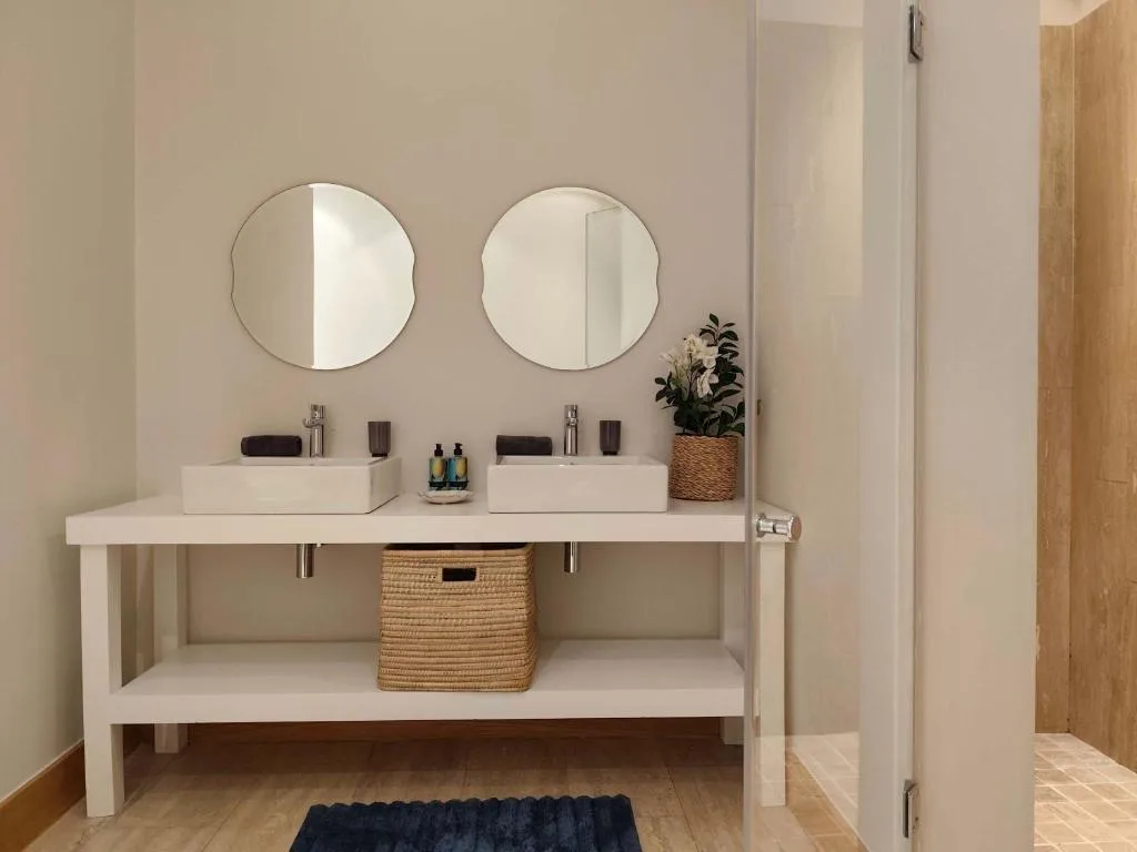 Modern dual vanity bathroom with round mirrors and potted plant decoration