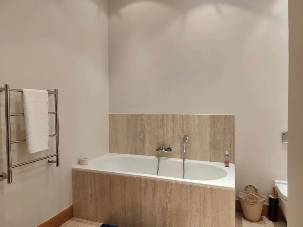 Modern bathroom with soaking tub, heated towel rail, and neutral tones
