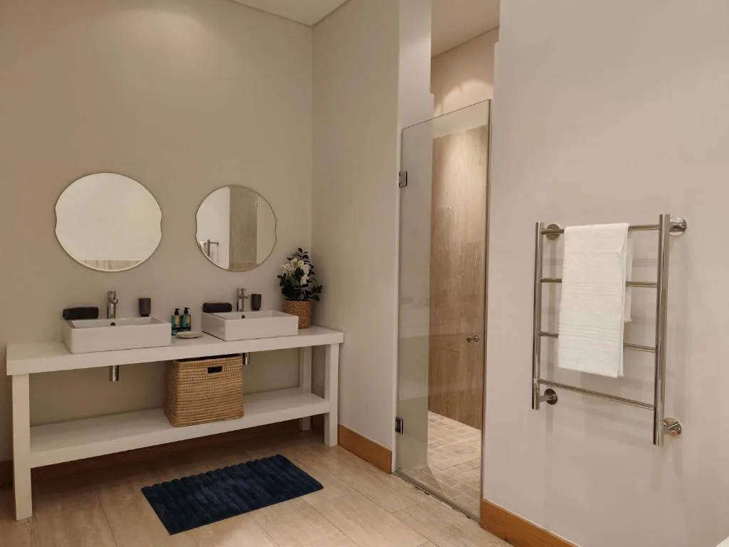Modern bathroom with dual vanity sinks, round mirrors, and heated towel rack