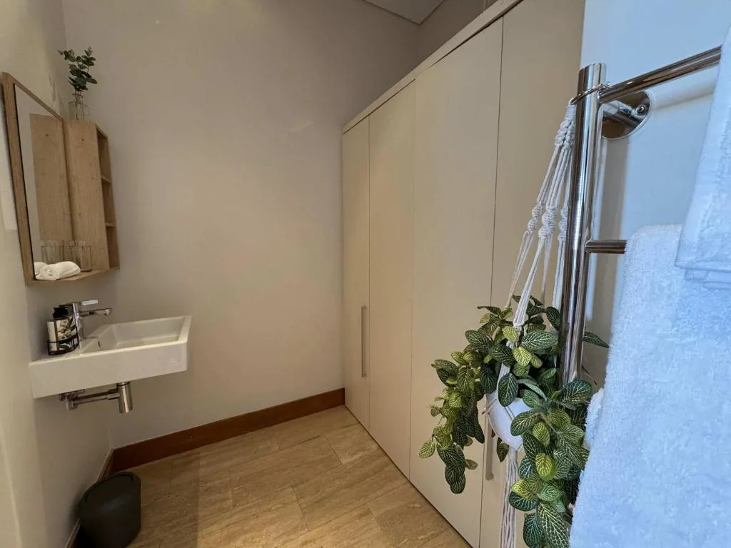 Modern bathroom with wall-mounted sink, heated towel rail, and potted plant