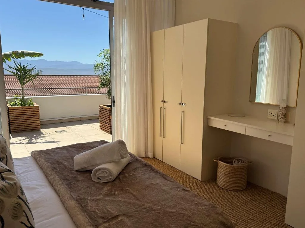 Bedroom with bed, wardrobe, vanity, and ocean view through glass doors