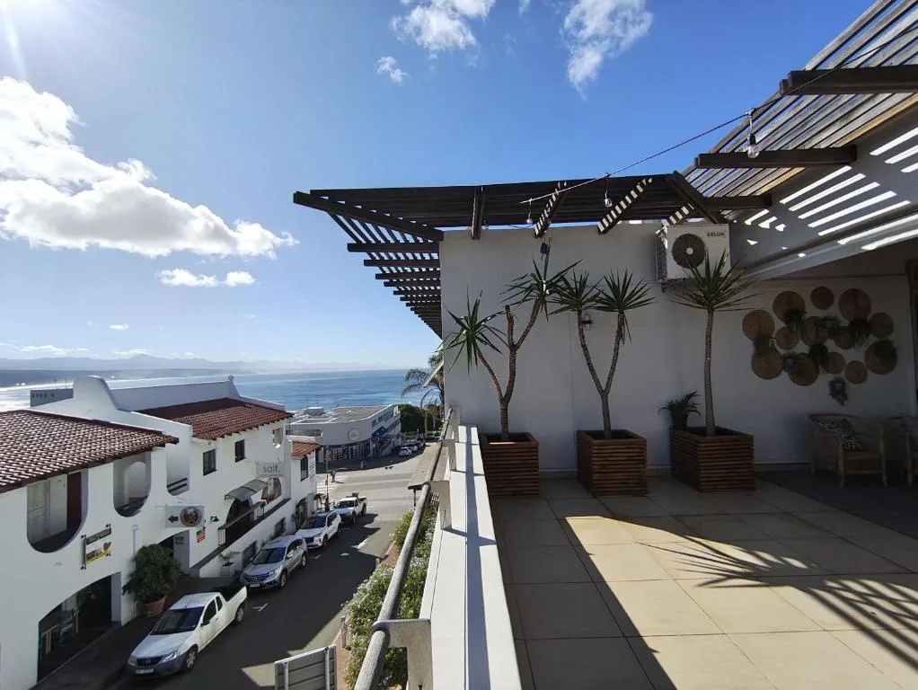 Spacious rooftop deck with pergola, potted palms, and ocean views