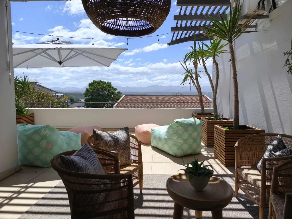 Shaded patio with wicker chairs, mountain views, and coastal landscape beyond