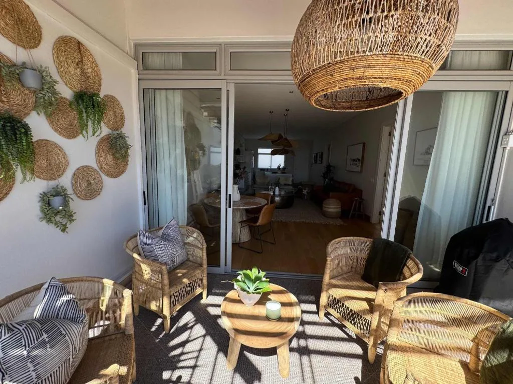 Outdoor patio with wicker furniture, potted plants, and woven wall decor