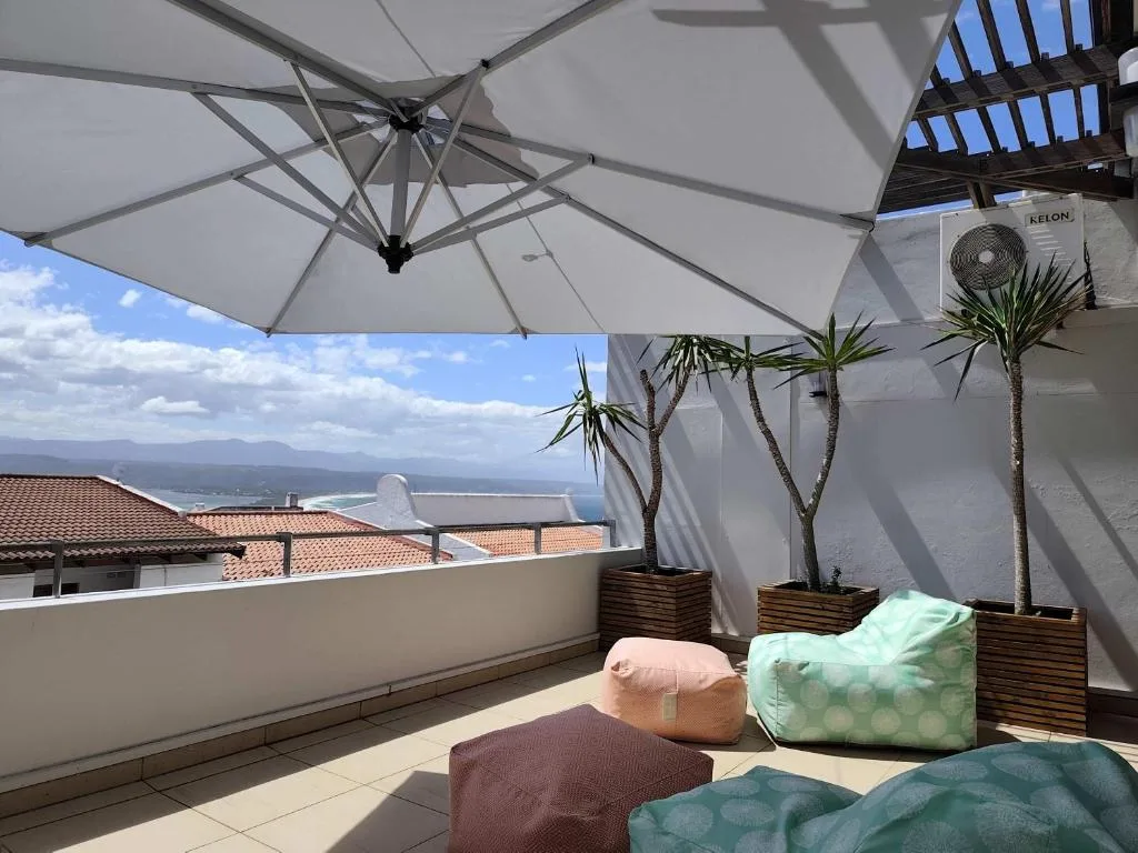 Shaded rooftop terrace with umbrellas, cushioned seating, and lagoon views