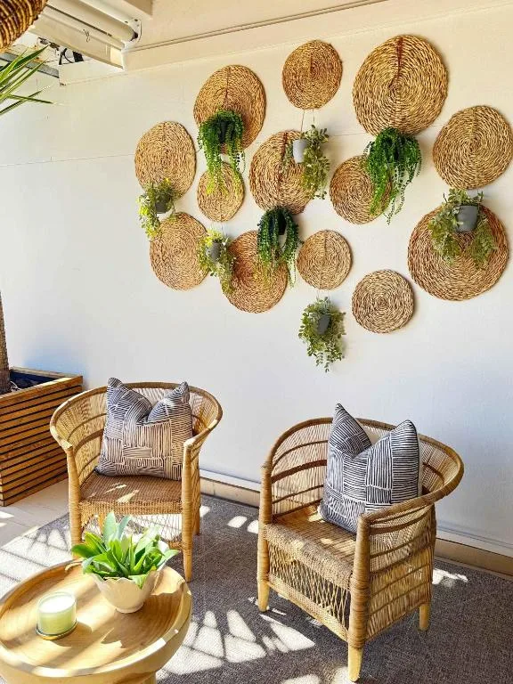 Woven basket wall art with trailing plants above rattan chairs