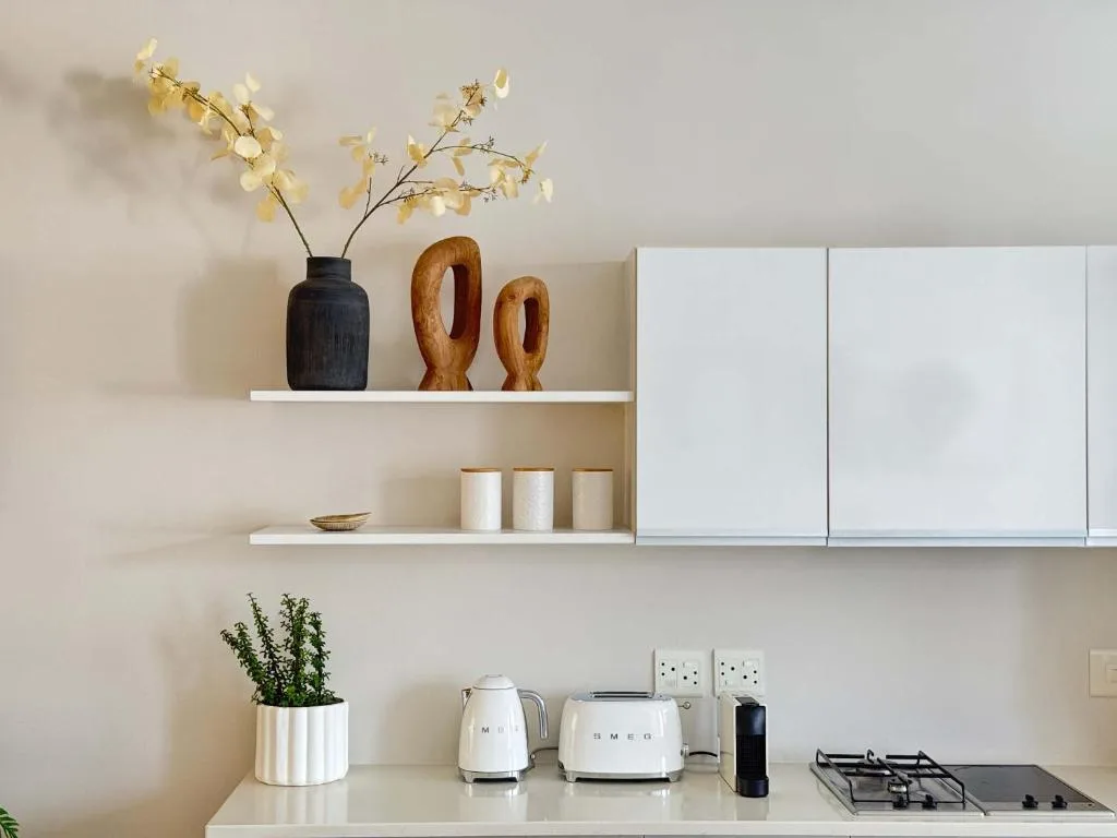 Modern kitchen counter with white appliances and decorative shelving