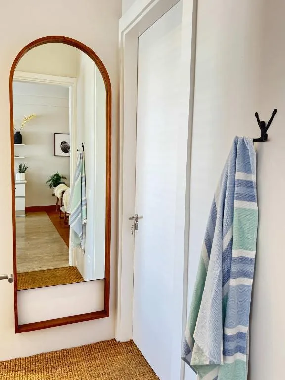 Wooden-framed mirror and folded striped towels in hallway entrance area