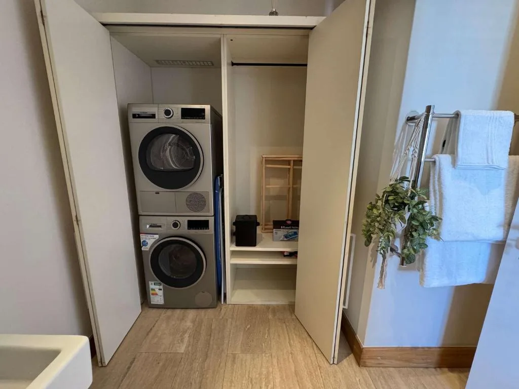Modern laundry room with stacked washer and dryer units and storage