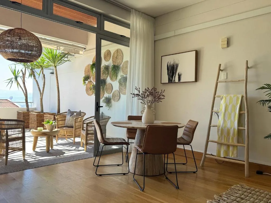 Modern dining area with round table, brown chairs, and ocean view doors