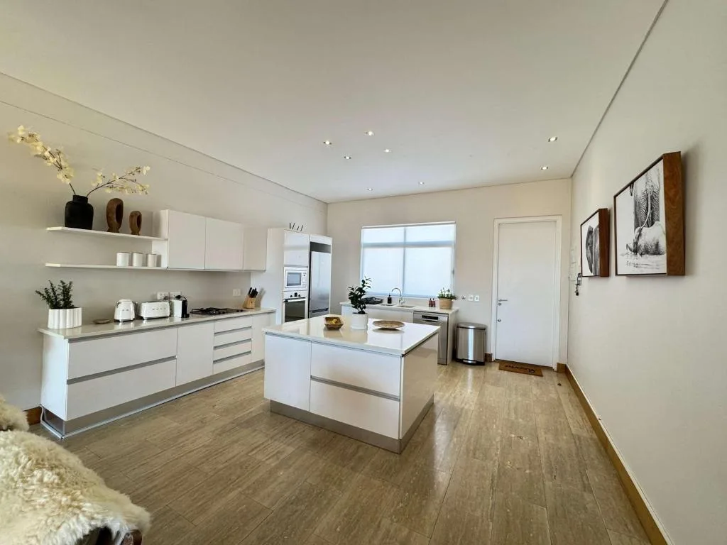 Modern white kitchen with island, stainless steel appliances, and ocean views