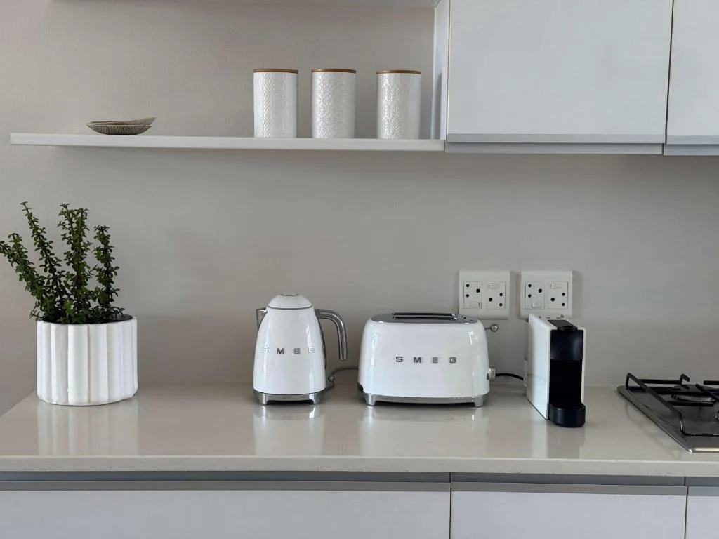 Modern kitchen counter with white appliances and fresh herbs in planter