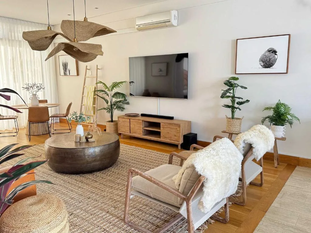 Modern lounge with TV, wooden furniture, plants, and designer lighting fixtures