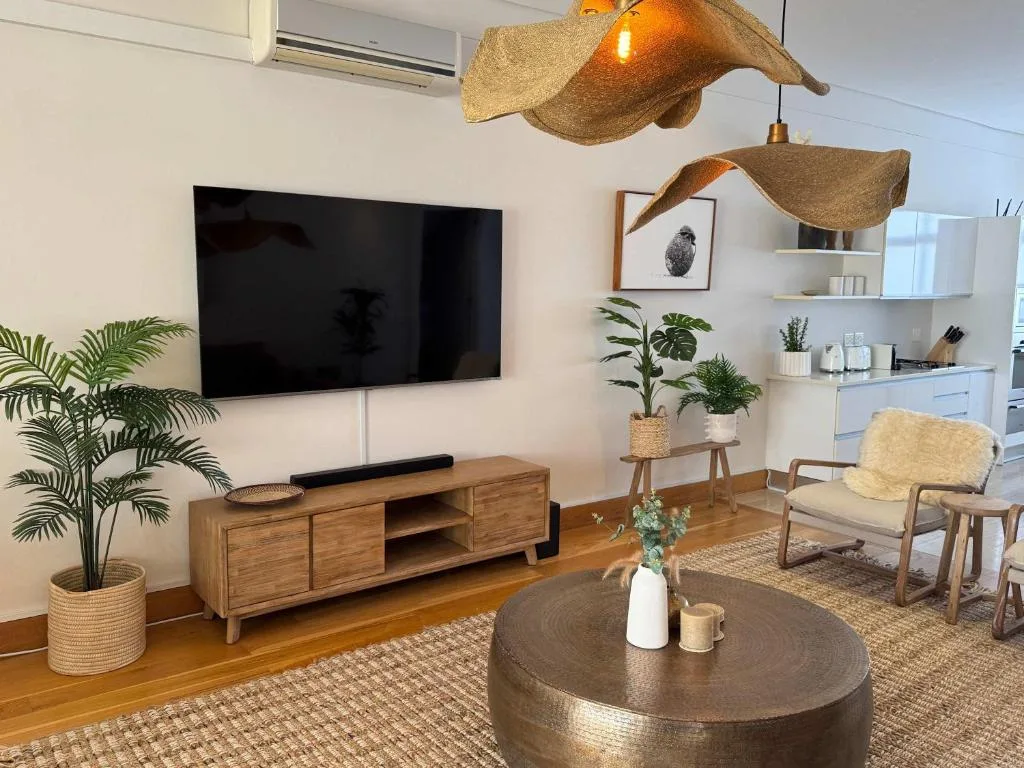 Modern lounge with wall-mounted TV, wooden furniture, and decorative lighting