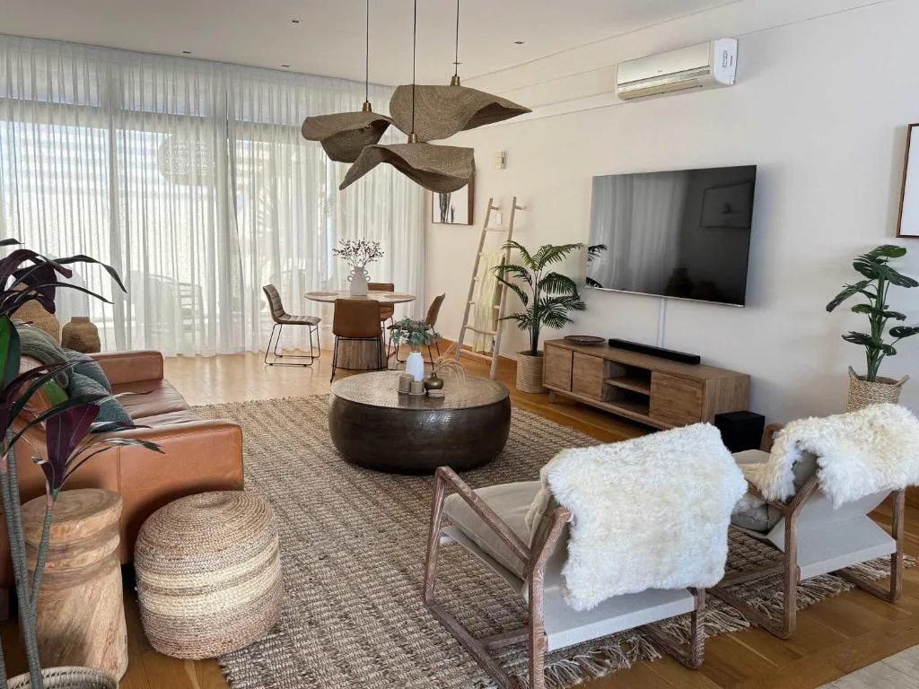 Spacious lounge with leather sofa, round coffee table, and wall-mounted television