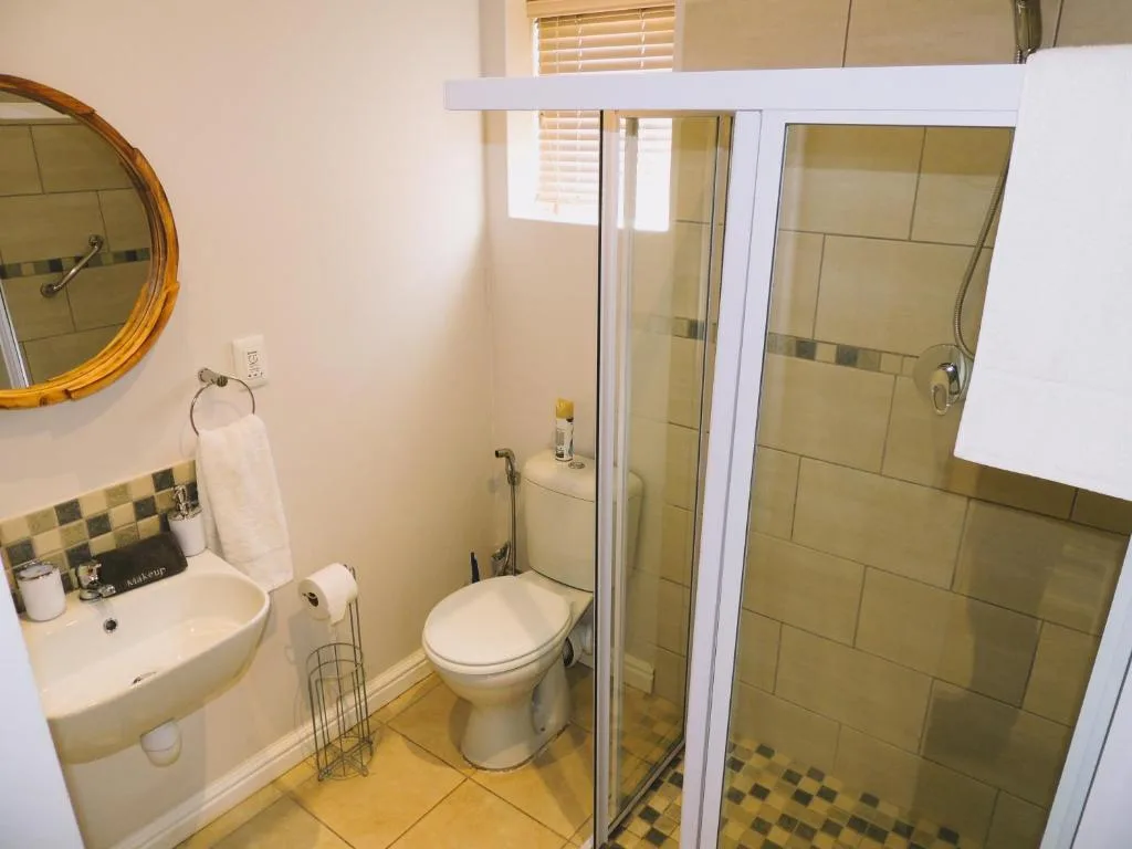 Modern bathroom with shower enclosure, toilet, and round mirror