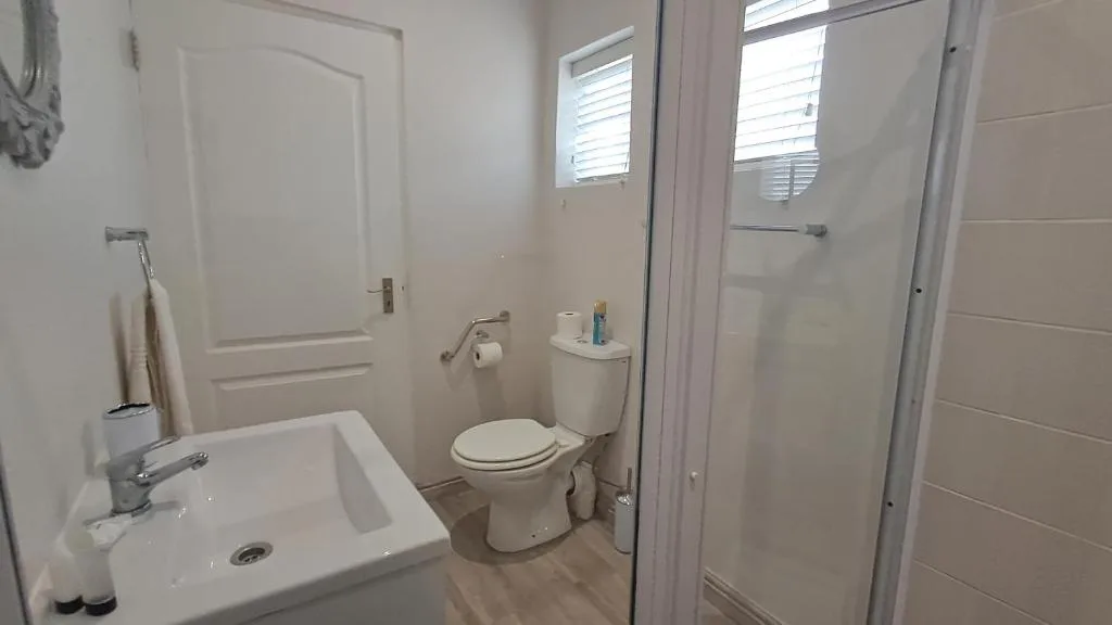 Clean bathroom with white sink, toilet, shower enclosure and windows