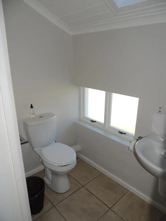 Bright bathroom with toilet, sink, and window overlooking gardens