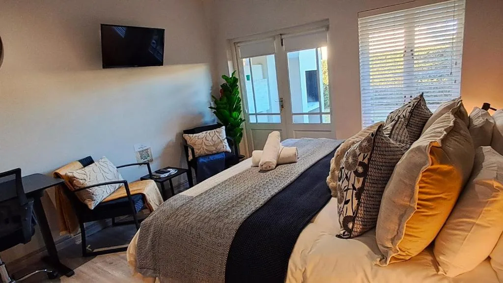 Spacious bedroom with queen bed, wall-mounted TV, and glass doors opening to balcony