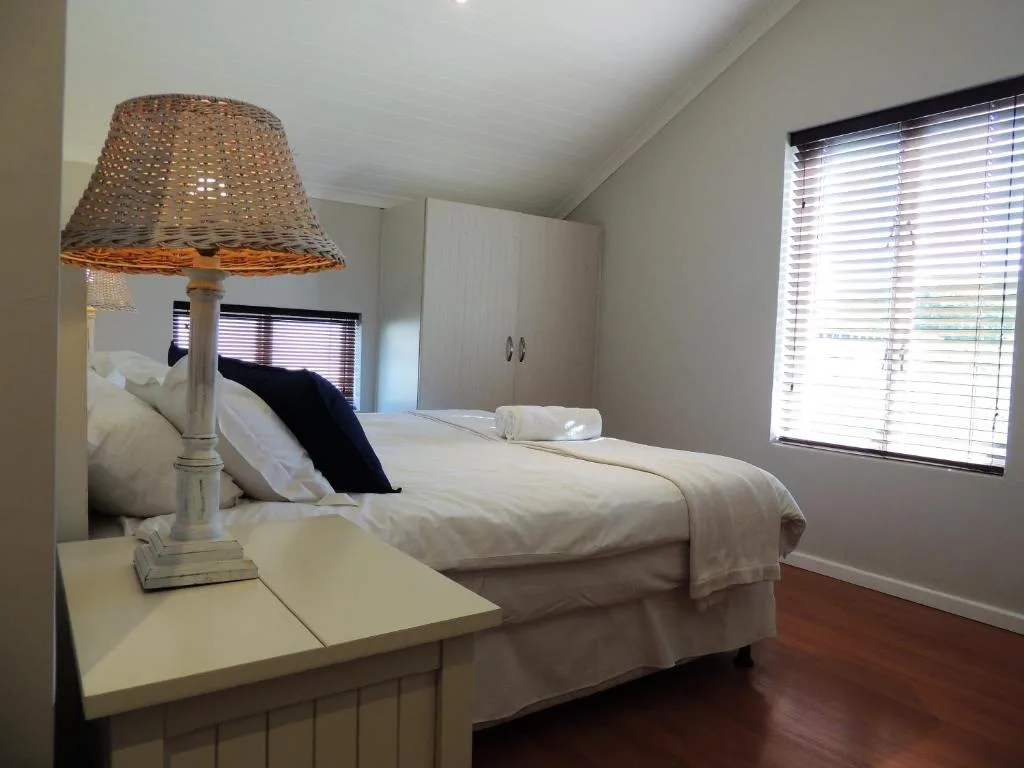Bright bedroom with queen bed, woven lamp, and ocean view windows