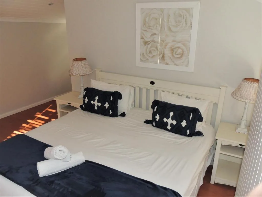 Bright bedroom with white bed, black decorative pillows, and warm afternoon light
