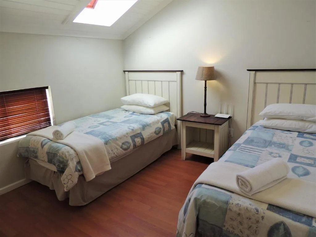 Bright bedroom with two single beds and wooden nightstand with lamp